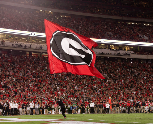 photo of UGA cheerleader running the super G flag onto the football field