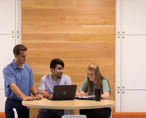 Students talk around a computer