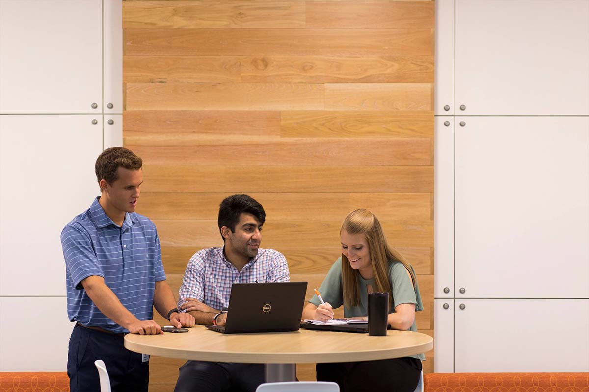 Students talk around a computer